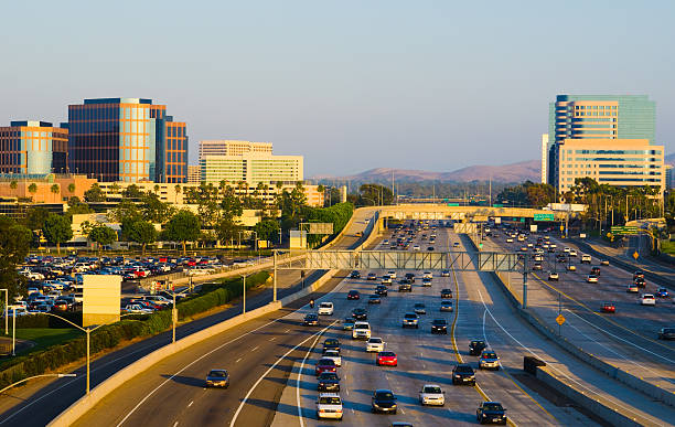 Irvine Skyline and freeway "Irvine office buildings on both sides of the 405 freeway. Irvine has the largest highrise office / business district in Orange County, and is located just beside the John Wayne Airport, the commercial airport that serves Orange County." san diego freeway stock pictures, royalty-free photos & images