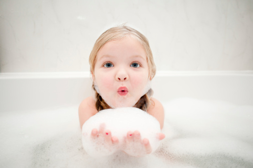 A cute little girl having fun in a bath full of bubbles!
