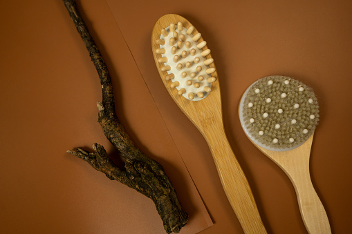wooden brush for anticellulite massage on a brown table. still life, spa procedures, wellbeing mock up. close up