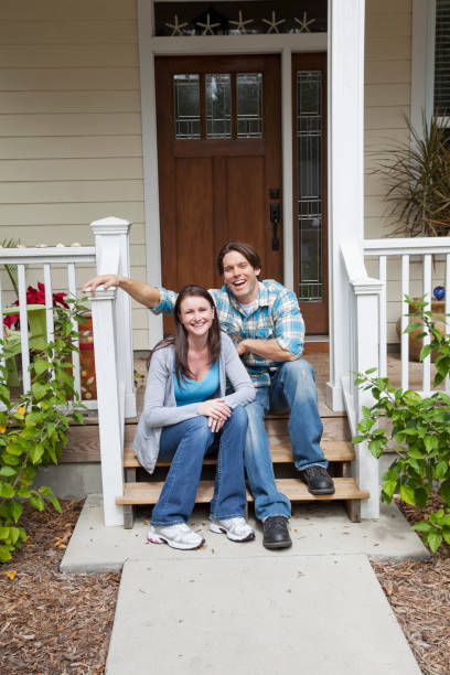 Couple sitting on front steps Mid adult couple sitting together on front steps of home. couple on front porch stock pictures, royalty-free photos & images