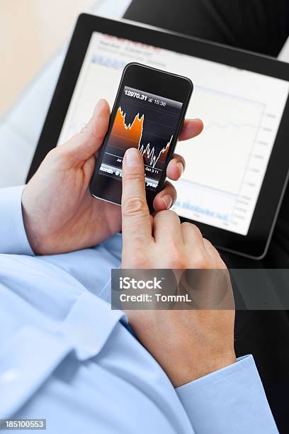 Foto de Homem Usando Smartphone E Tablet Digital e mais fotos de stock de Adulto - Adulto, Analisar, Ação da Bolsa de Valores