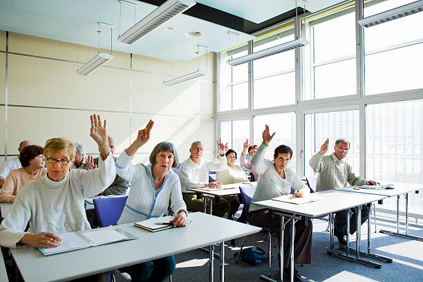 istock Senior students in education room listening lecture....raising hands 185100863
