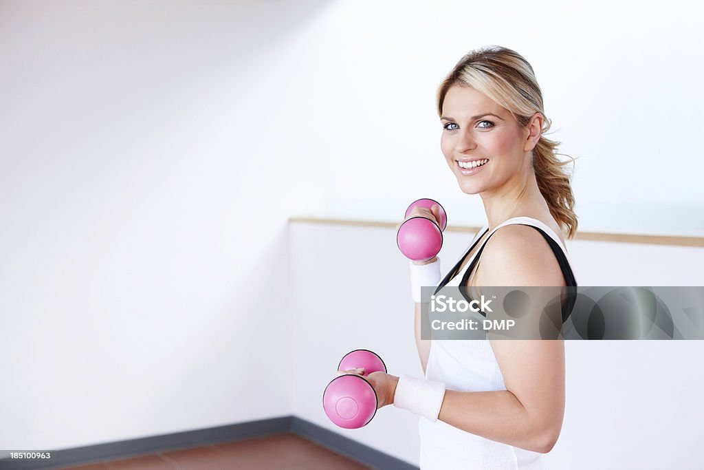 Młoda kobieta z hantle w siłowni instruktora - Zbiór zdjęć royalty-free (Aktywny tryb życia)