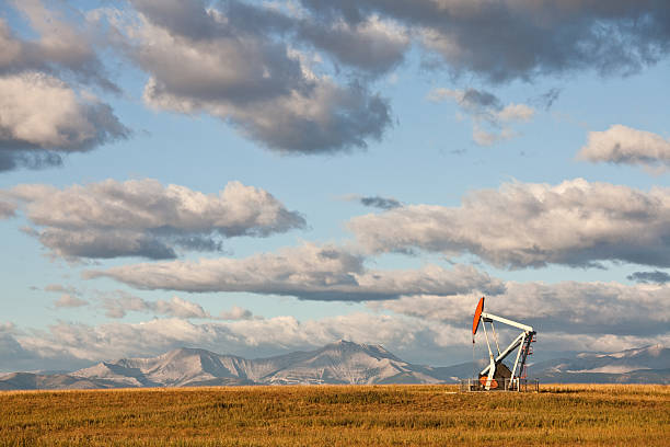 Prairie Pumpjack in Alberta Canada A pumpjack on the prairie. Alberta, Canada.Rocky Mountains in distance. Crude oil and the oil industry in general is a huge industry in Western Canada. Additional themes here include natural gas, fossil fuel, energy, gas, power, scenic, landscape, oil field, oilsands, pipeline, oil rig, geology, engineering, and fracking.  oil pump photos stock pictures, royalty-free photos & images