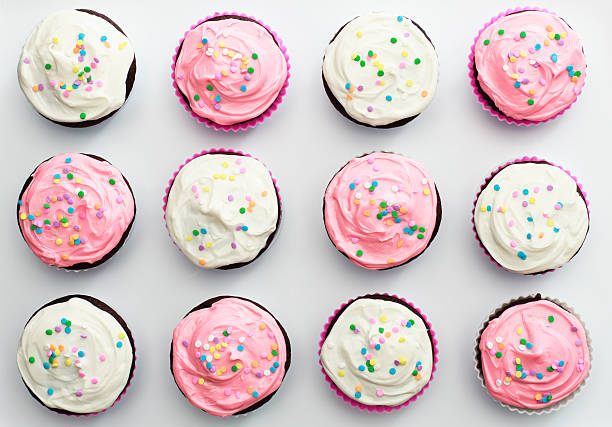 Arrangement of 12 pink and white sprinkled cupcakes stock photo