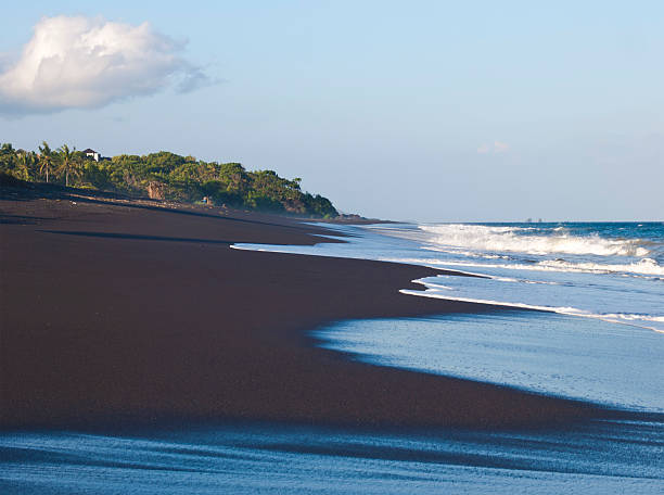 Black sand beach "Waves on Long Black sand beach southwest from Padangbai on island Bali, Indonesia." black sand stock pictures, royalty-free photos & images