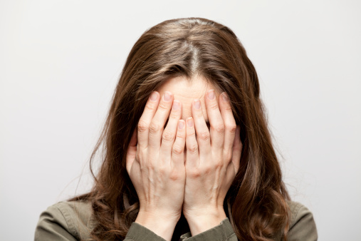 Woman hides her face behind her hands