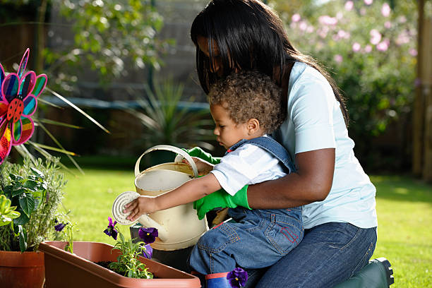 accompagnatore/childminder giardinaggio con bambino piccolo - baby1 foto e immagini stock
