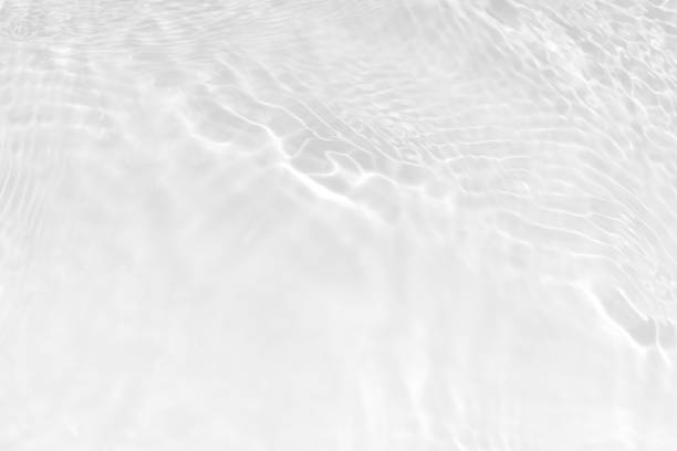 White water with ripples on the surface. Defocus blurred transparent white colored clear calm water surface texture with splashes and bubbles. Water waves with shining pattern texture background.