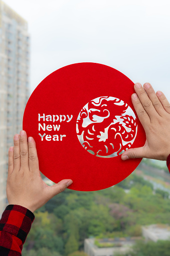 man sticking a Chinese New Year of the Dragon decoration to a window at vertical composition and no logo no trademark