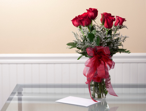 Love concept with blank card and roses on a glass table.