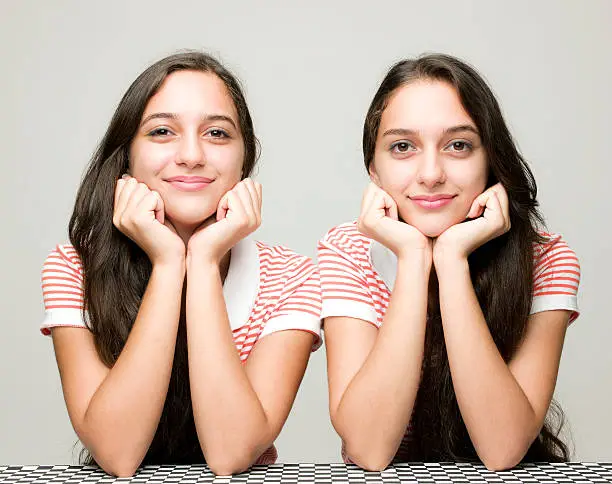 Two twin teenage sisters smiling at camera