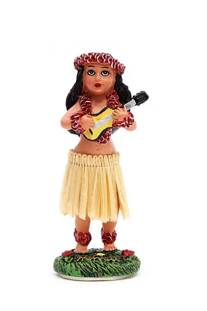 This is a closeup view of a vintage style hula girl dashboard bobble doll playing a ukulele.