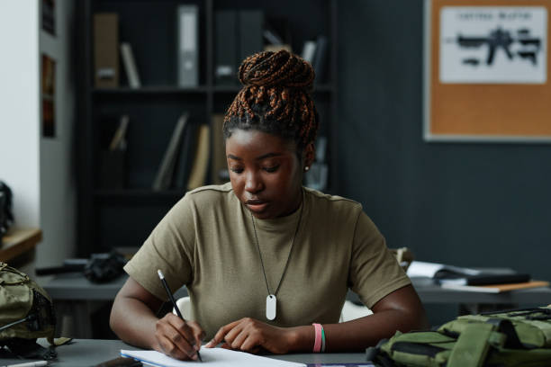 istock Young black woman in t-shirt making notes in notepad while sitting by desk 1851057855