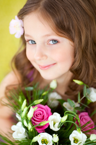 Portrait of cute smiling girl with flowers looking at camera.