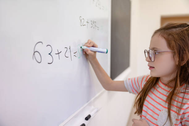 istock Little girl counting math equation on whiteboard in school. 1851060013