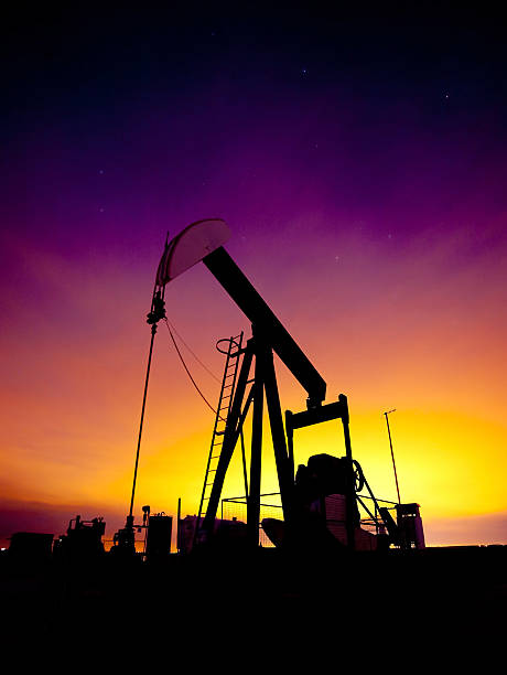 Pumpjack at sunset A pumpjack silhouetted by a vibrant sunset. oil pump oil industry alberta equipment stock pictures, royalty-free photos & images