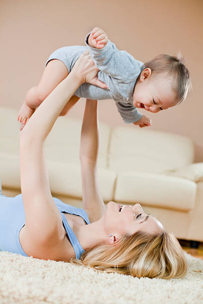 istock Mother laying on floor playing with her baby 185107744