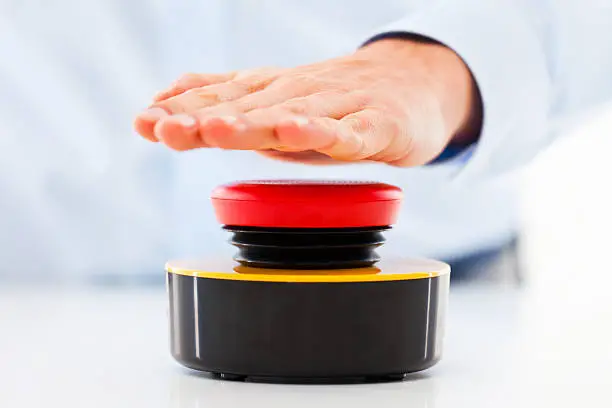 Hand of a man hitting an unlabled  game buzzer.