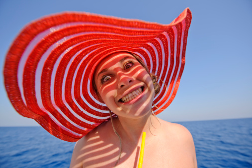 funny woman grimacing in summer time with red hat.