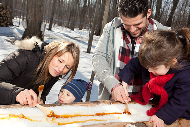 familie essen ahorn-toffee auf sticks - maple syrup tree sap stock-fotos und bilder