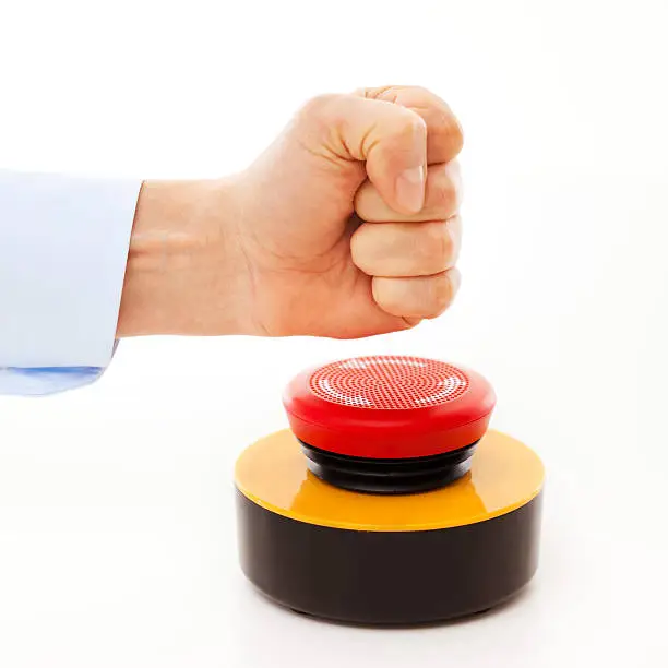 Hand of a man hitting an unlabled  buzzer.