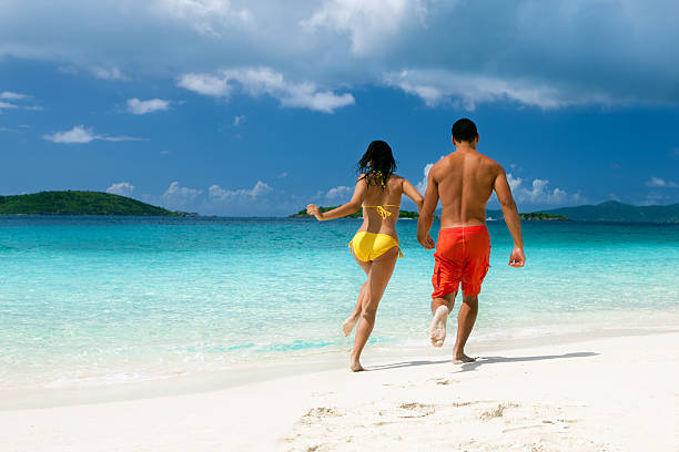 couple jogging le long de la côte sur la plage des caraïbes - swimwear caribbean sea beach water photos et images de collection