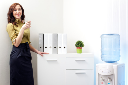 Businesswoman having a break in the office with glass of water from Water Cooler