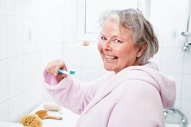 istock senior woman brushing teeth 185110484