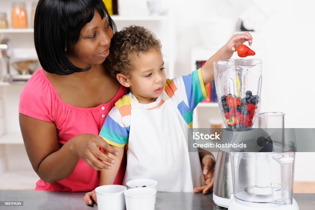 Biracial enfant aidant sa mère préparer un Smoothie - Photo de Cocktail de fruits pressés libre de droits