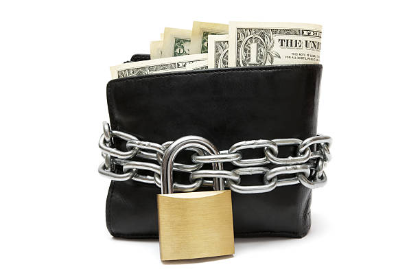 Black wallet with a lock and chain around it Black leather wallet full of Dollar banknotes locked with chain and padlock. Isolated on a white background. chain object stock pictures, royalty-free photos & images