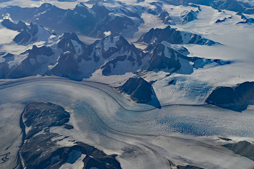 Aerial view of mountains, snowfields and glacier in southern Greenland on clear sunny autumn day.