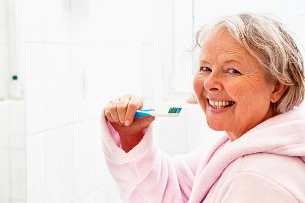 istock senior woman brushing teeth 185112236