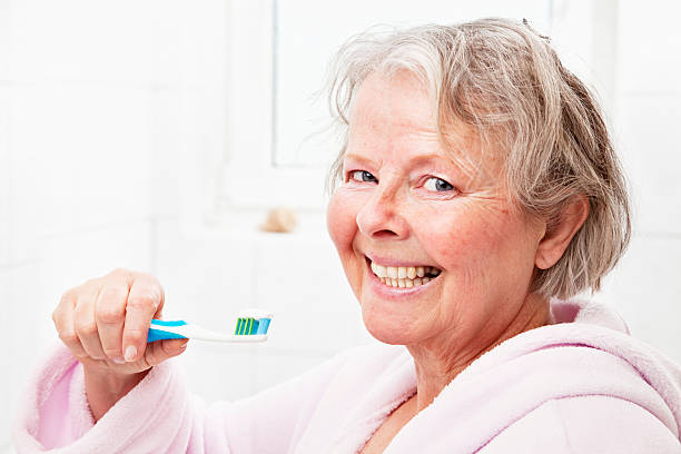 istock senior woman brushing teeth 185112398