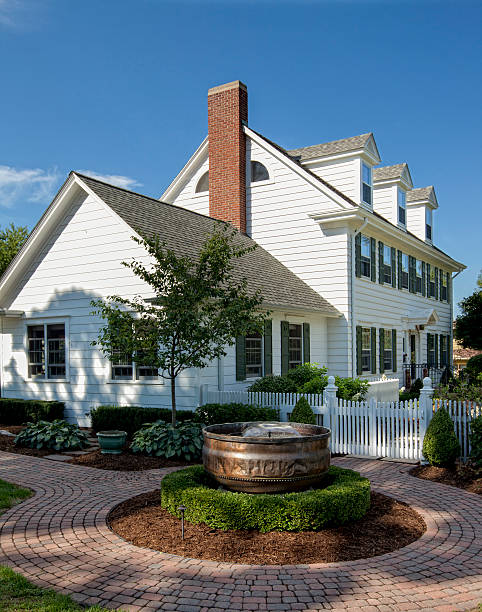 White, colonial style house with landscaping on a clear day