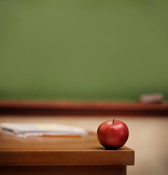 Red apple on teacher's desk. stock photo