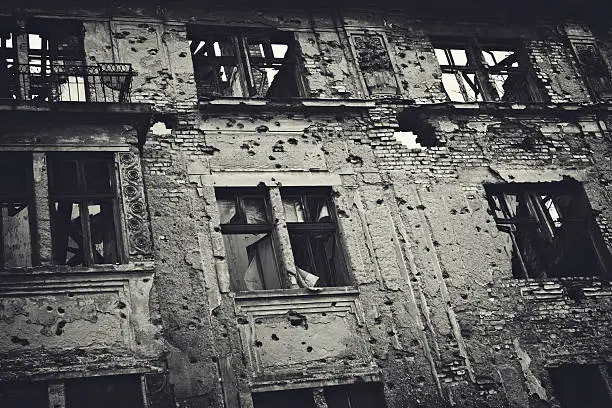 Residental building facade heavily damaged in the Balkans war. Toned image.