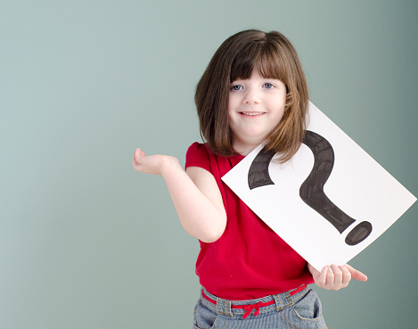little girl looks unsure holding a question mark