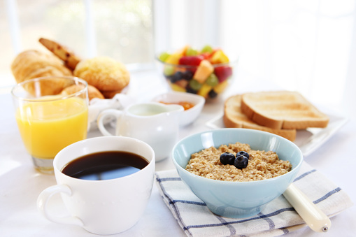 A top view of serving table for breakfast, pancakes with berries, syrup and cup of flat coffee