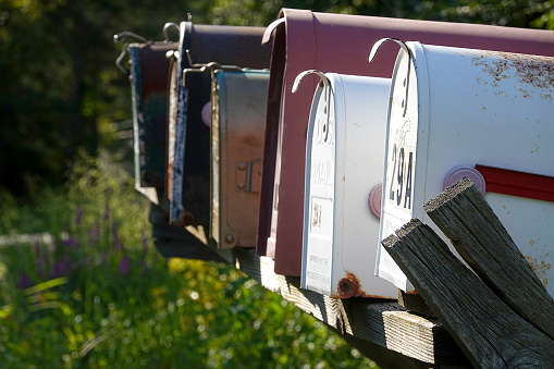 A large black metal mailbox along a quiet country road