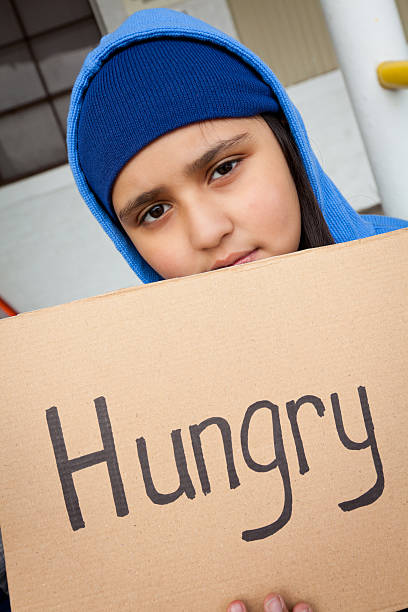 istock Sad young girl asking for help with a hungry sign 185116928