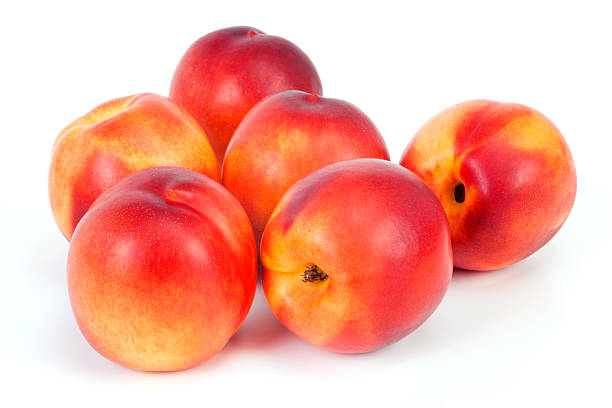 Bunch of nectarines on white table  Group of nectarines on white background. Selective focus, shallow DOF. nectarine stock pictures, royalty-free photos & images