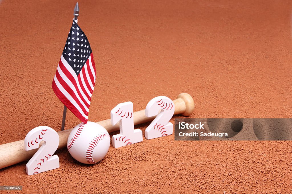 Baseball 2012 Season Year 2012 next to a baseball bat and USA flag on orange colored clay warning track.  Numbers two and one are made out of wood and have red stitches like a baseball.  (Shallow depth of field) 2012 Stock Photo