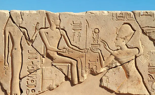 "A sunk relief from the First Court of the mortuary temple built by the 13th century BC pharaoh Seti I (also Sethos I, Sethi I, Sety I and Menmaatre).  The relief depicts the pharaoh (on the left) making an offering to two gods, possibly Amun and his consort Mut.  Each of the gods carries the ankh, symbol of life, in their right hand.  The decoration is of particularly high quality.  The temple is located on the West Bank near Dra Abu el-Naga."