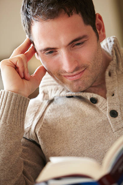 istock Young man reading book at home 185119805
