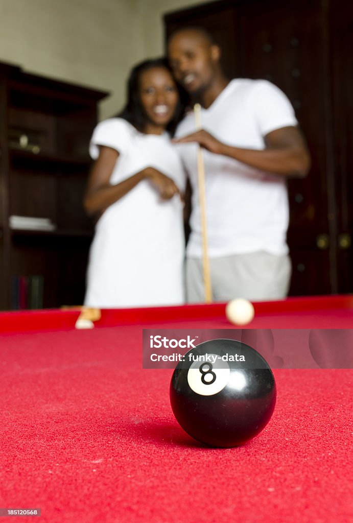 African couple playing pool An African couple is playing pool and they are in the eve of potting the 8. Selective focus.See also the other version (focus on the couple) 25-29 Years Stock Photo