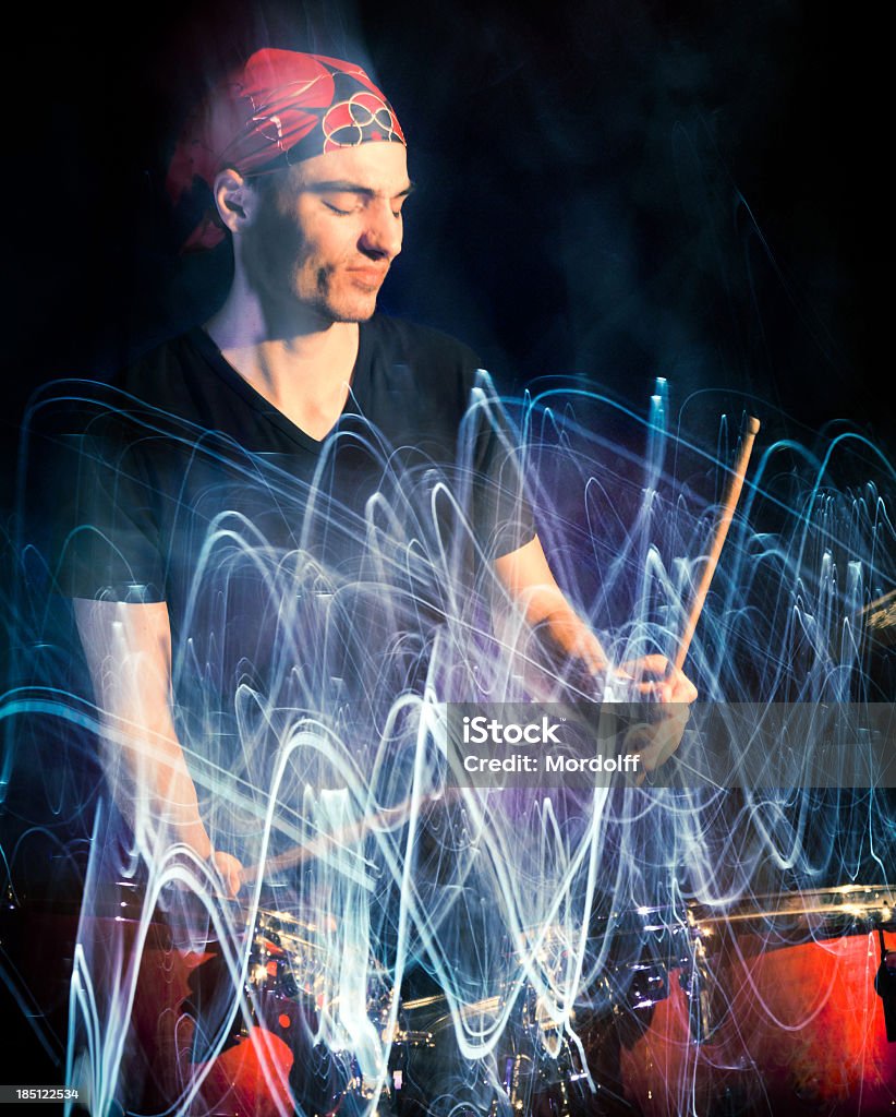 Músico tocando tambores en la oscuridad, con luz traza - Foto de stock de Desenfocado libre de derechos