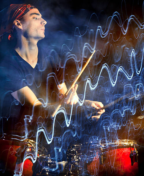 Musician playing drums in dark with pulsating light trace