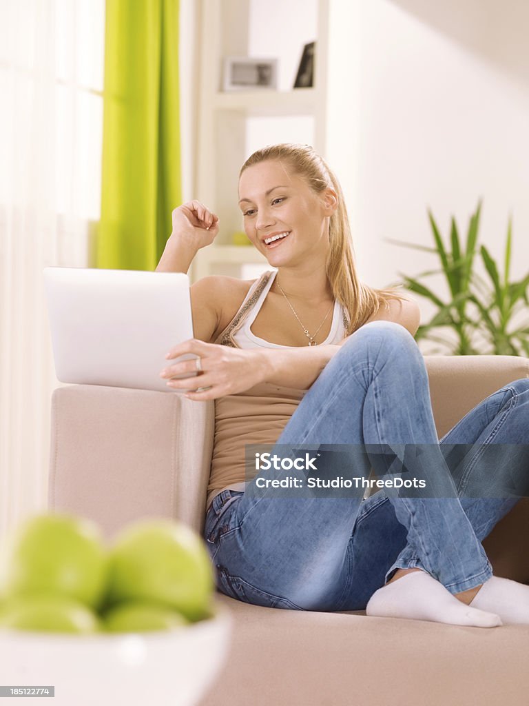 young woman using a tablet PC Young happy woman sitting on the sofa and using a tablet computer . 20-24 Years Stock Photo