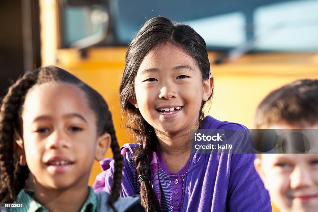 Bambini in piedi fuori scuola bus - Foto stock royalty-free di Bambino